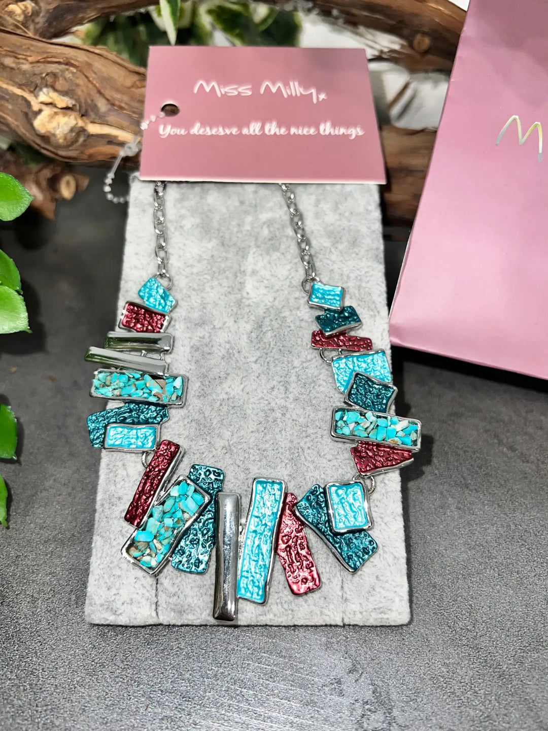 A vibrant turquoise and red mosaic statement necklace with silver-toned metal accents, displayed on a branded card from miss milly.